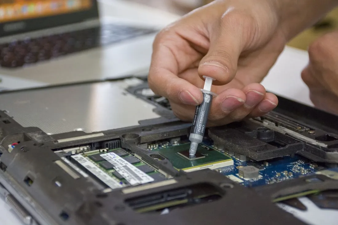 Técnico aplicando pasta térmica sobre el procesador de una laptop