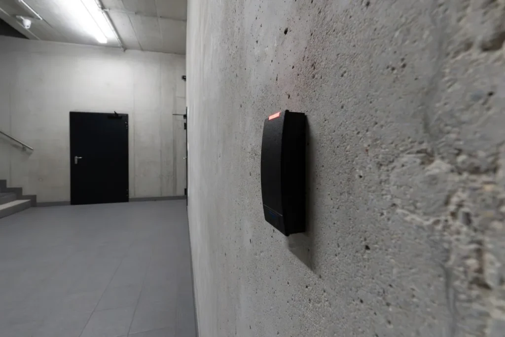 Persona acercando una tarjeta a un lector de control de acceso en la puerta de una oficina