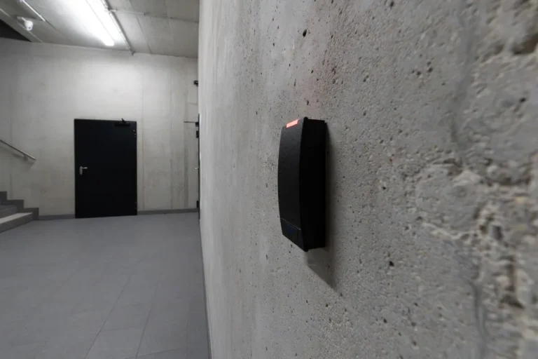 Persona acercando una tarjeta a un lector de control de acceso en la puerta de una oficina
