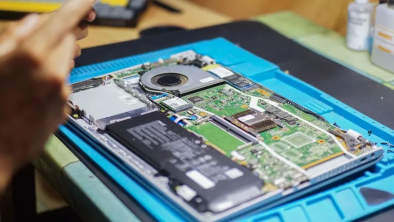 Repuestos de laptop desarmados sobre una mesa: teclado, batería y placa